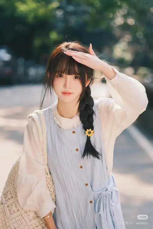 Dưới bóng cây ngoài trời, cô gái mặc sơ mi trắng giơ tay che nắng, tóc đen buộc nơ và biểu cảm bình yên